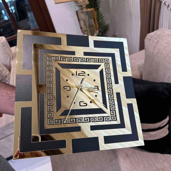 a hand holding black and golden color clock