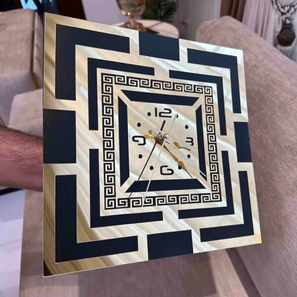 a hand holding black and golden color clock