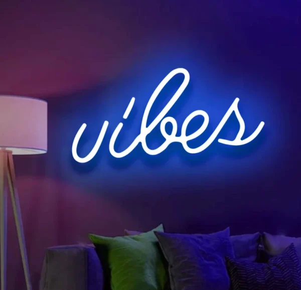 a neon light on the wall displays the text vibes