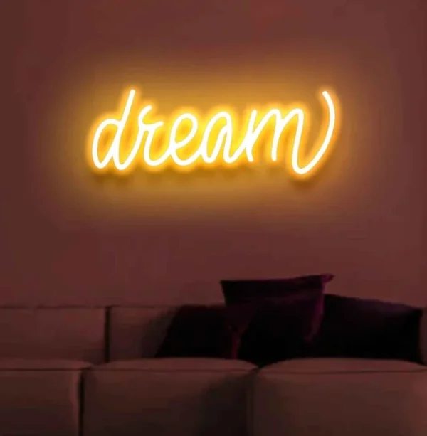 a neon light on the wall displays the text dream