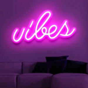 a neon light on the wall displays the text vibes. Vibes Neon Sign - Neon Light